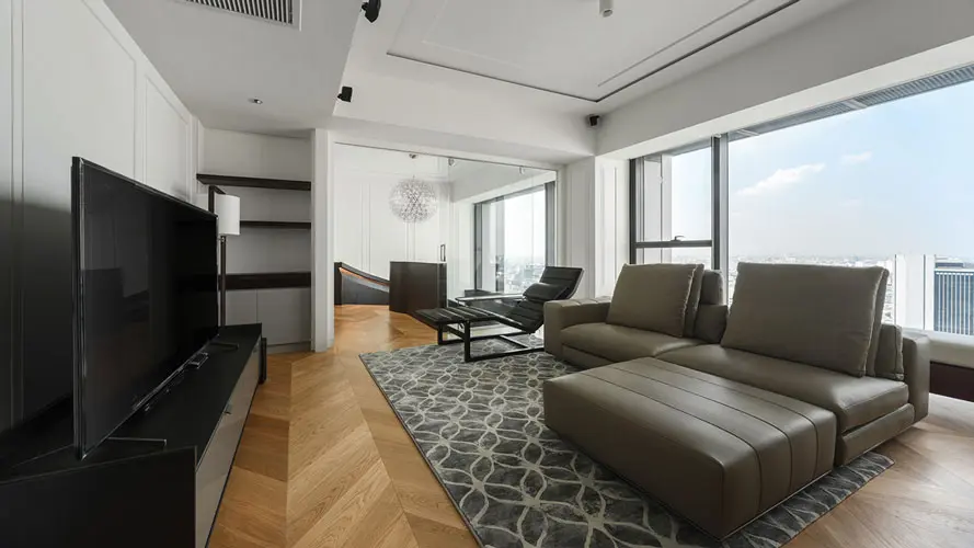 Living room with a taupe leather sectional sofa, glass coffee table and skyline view