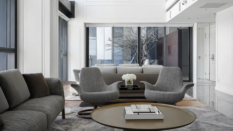 Living room with curved gray armchairs and sofa around a round wood coffee table